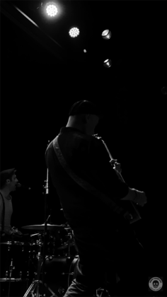Bassist lehnt sich in sein Instrument. Fotografiert von hinten, sehr dunkel und in schwarz weiß.